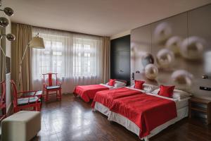 布拉格珀拉酒店的两张位于酒店客房的床铺,配有红色床单