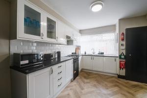 利物浦Poppy's Place - Manningham Road的厨房配有白色橱柜和黑色家电