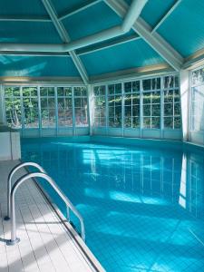 宁斯佩特文宁达尔别墅庄园酒店的室内游泳池设有蓝色瓷砖地板和窗户。