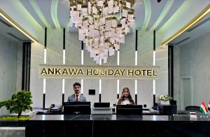 埃尔比勒Ankawa Holiday Hotel的一位坐在亚马逊假日酒店办公桌旁的男女