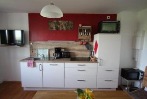 劳特拉赫Hof Lebenslust für Mensch und Tier的厨房配有白色橱柜和红色墙壁