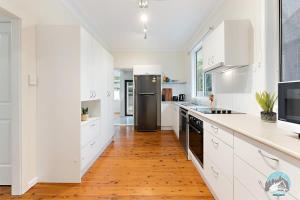 悉尼Aircabin - North Ryde - Sydney - 4 Beds House的厨房配有白色橱柜和黑色冰箱。