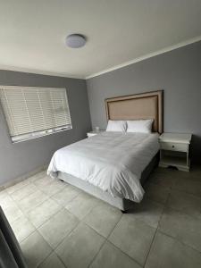 东伦敦Grandview adventure and guesthouse的卧室设有一张白色大床和一扇窗户。