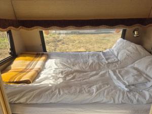 SynesVintage caravan的一张未铺好的床铺,放在带窗户的露营车里
