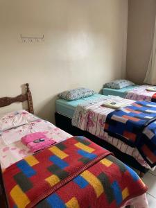 欧鲁普雷图Pousada Zacarias的一间设有三张床和色彩缤纷的毯子的房间