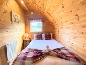 KeltyPond View Pod 1 with Outdoor Hot Tub - Pet Friendly - Fife - Loch Leven - Lomond Hills的木制客房内的一间卧室,配有一张床