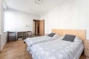 格但斯克Apartament Świętego Ducha 3234的卧室设有两张床,拥有白色的墙壁和木地板