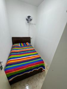 沙迦Al Majaz Partition & Rooms的一张床上,床上有一条色彩缤纷的条纹毯子