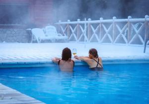 拉安戈斯图拉镇ONA Apart Hotel and Spa的两个女人在游泳池里喝一杯葡萄酒