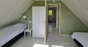 WoudsendDe Rakken的阁楼卧室设有两张床和楼梯。