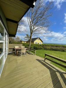 宝可波Summer House At Hvidbjerg Beach With Sea View的木屋的木甲板上配有桌子和长凳