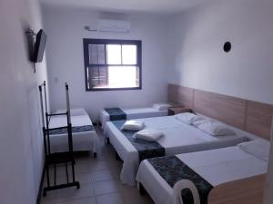 卡纳内亚Golfinho Plaza Hotel的带三张床和窗户的客房