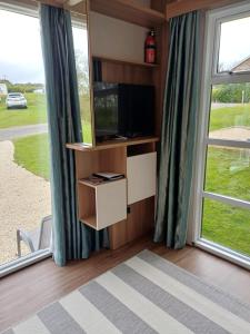 盖尔文Luxury Pods at Mornest Caravan Park, Anglesey的一间带电视和大窗户的客厅