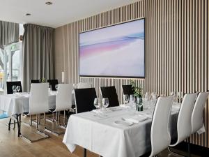 海宁格松Quality Hotel Maritim的一间会议室,配有白色的桌椅和投影屏幕