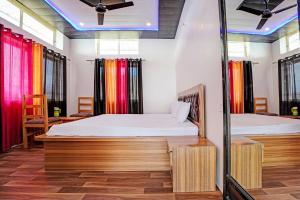 奈尼塔尔Super OYO Sadhna Holiday Home的配有色彩缤纷窗帘的客房内的两张床