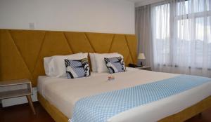马尼萨莱斯Pop Art Hotel Manizales Centro Histórico的一间卧室配有一张带蓝白色枕头的大床