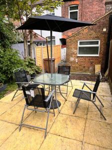 卢顿Visit Luton With This 2 BR Rental - Sleeps 6的庭院内桌椅和遮阳伞