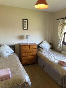 斯皮德尔Spiddal Cottage的一间带两张床和木制梳妆台的卧室