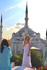 伊斯坦布尔Blue House Hotel Old City - Sultanahmet的站在建筑物前身穿白色衣服的女人