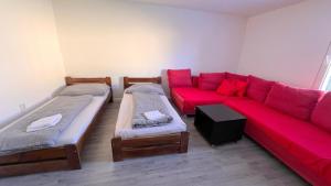 塞内奇Apartmánový dom Most pri Bratislave的客厅配有两张床和一张红色沙发