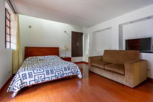 波哥大拉坎德拉里亚公寓式酒店的一间卧室配有一张床和一张沙发