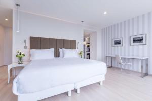普埃布拉NH Puebla FINSA的白色卧室配有一张白色大床和书桌