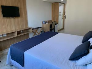 彼得罗波利斯Apartamento Hotel Itaipava Petropolis的一间卧室配有一张带蓝色床单和枕头的床。