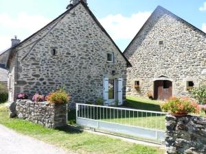 SarrouxGîte de France à Sarroux - St Julien 3 épis - Gîte de France 8 personnes 134的一座古老的石头建筑,前面有栅栏