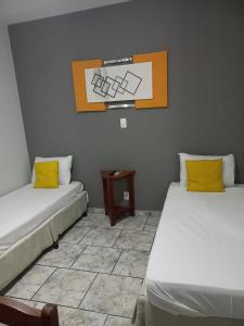 巴乌鲁Alliance Hotel的客房设有两张带黄色枕头和桌子的床。