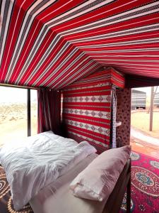 瓦迪拉姆Wadi Rum Trip的红色和白色天篷的房间里一张床位