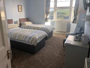 伊尔弗勒科姆瓦利屋酒店的一间卧室设有两张床、一张桌子和一个窗口。
