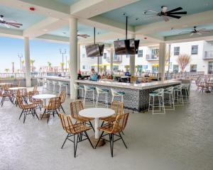 默特尔比奇Holiday Inn Club Vacations Myrtle Beach Oceanfront, an IHG Hotel的一间带桌椅的餐厅和一间酒吧