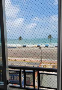 蒙加瓜Apartamento pé na areia de frente para o mar的透过栅栏可欣赏到海滩景色