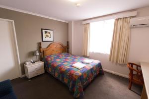 奥克利查斯顿行政汽车旅馆的一间小卧室,配有床和窗户