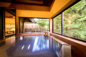 南小国町Satonoyu Waraku 13 years or older的一座室内游泳池,位于带大窗户的房屋内