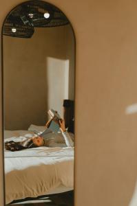 El PorvenirEqu Hotel de Tierra的躺在床上的女人在镜子里读书