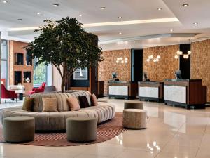克拉科夫克拉科夫丽笙大酒店的中间有一个带沙发和一棵树的大堂
