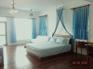 Huxi海天一舍民宿的一间卧室配有一张带蓝色窗帘的床和一张书桌