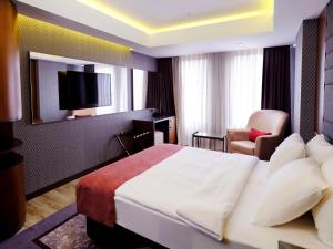埃斯基谢希尔Nova Vista Deluxe & Suites a Member of Radisson Individuals的酒店客房配有一张床、一把椅子和一台电视。