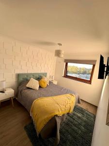洛斯安赫莱斯Confortable Dpto 2D y 2 baños的一间卧室配有一张带黄色床单的床和一扇窗户。
