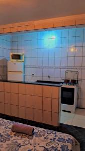 瓜鲁柳斯Casa kitnet的瓷砖厨房配有炉灶和微波炉