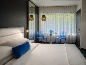 波特兰朱庇特酒店的一间卧室配有一张床和一张带蓝色椅子的桌子