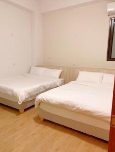 马公旅行者背包客栈 的配有白色墙壁和木地板的客房内的两张床