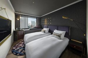 东京Mercure Tokyo Hibiya的酒店客房设有两张床和电视。