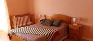 拉日什杜皮库Casa das Pedras Altas的一间卧室配有一张带2个床头柜和1张婴儿床的床。