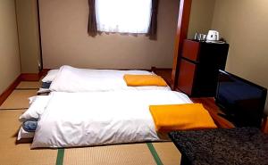 Inaiビジネスホテルパークイン石巻的一间卧室配有两张带黄色枕头的床和电视。