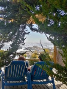 埃尔基斯科CasaMar ElQuisco的两个人坐在蓝色长椅上,看着大海