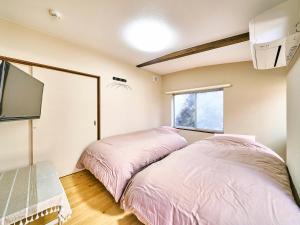 新宫市Kokoyui Guesthouse Shingu的配有电视的客房内的两张床