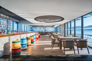 岘港voco Ma Belle Danang, an IHG Hotel的餐厅设有酒吧,配有桌椅