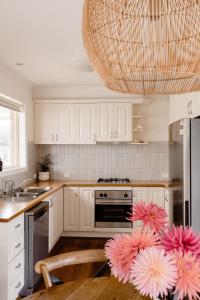 仙女港Banksia Beach House的厨房配有白色橱柜和吊灯。